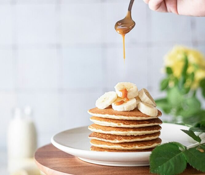 panquecas de banana em um prato branco com whey protein