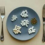 Um prato com várias cápsulas de suplementos para emagrecer com garfo e faca ao lado